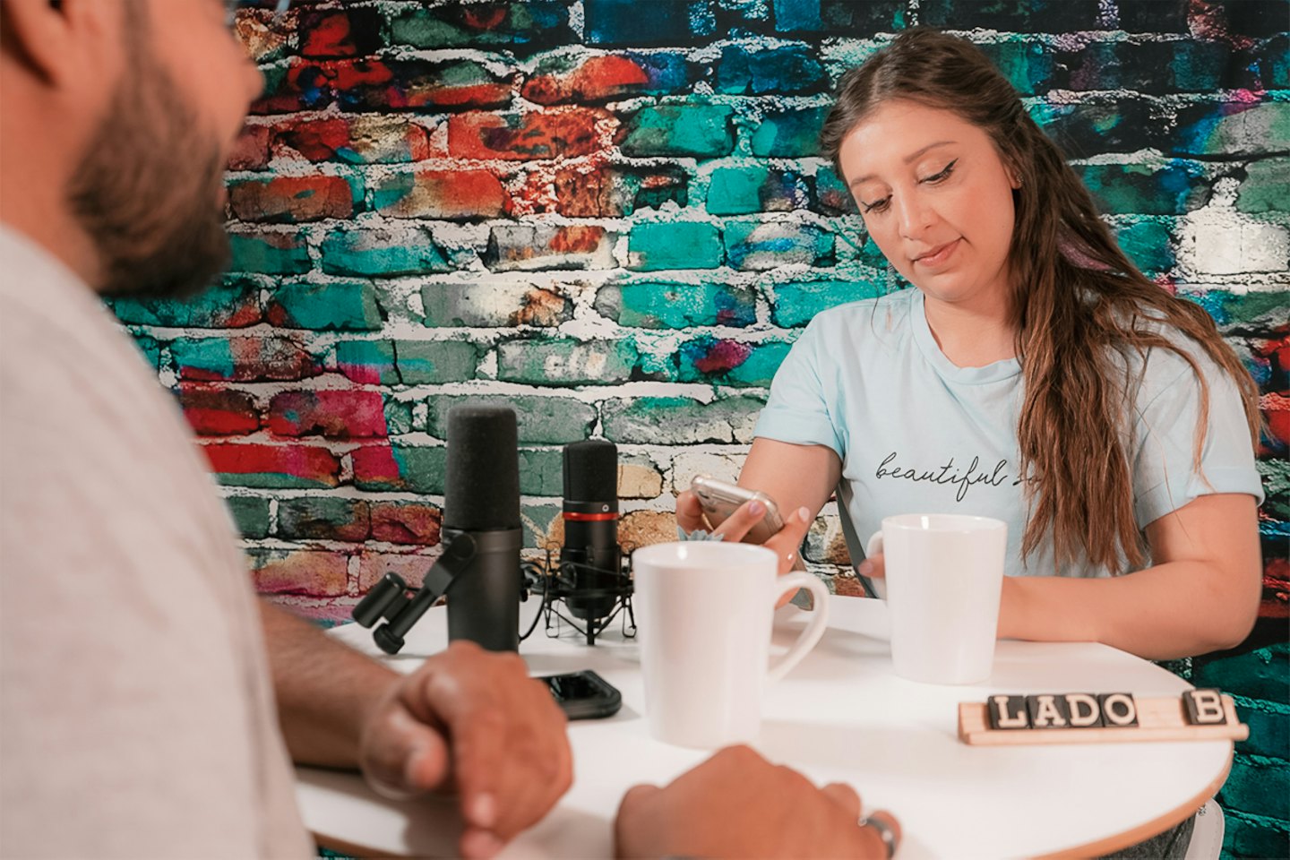 Two people recording a podcast at a white table.