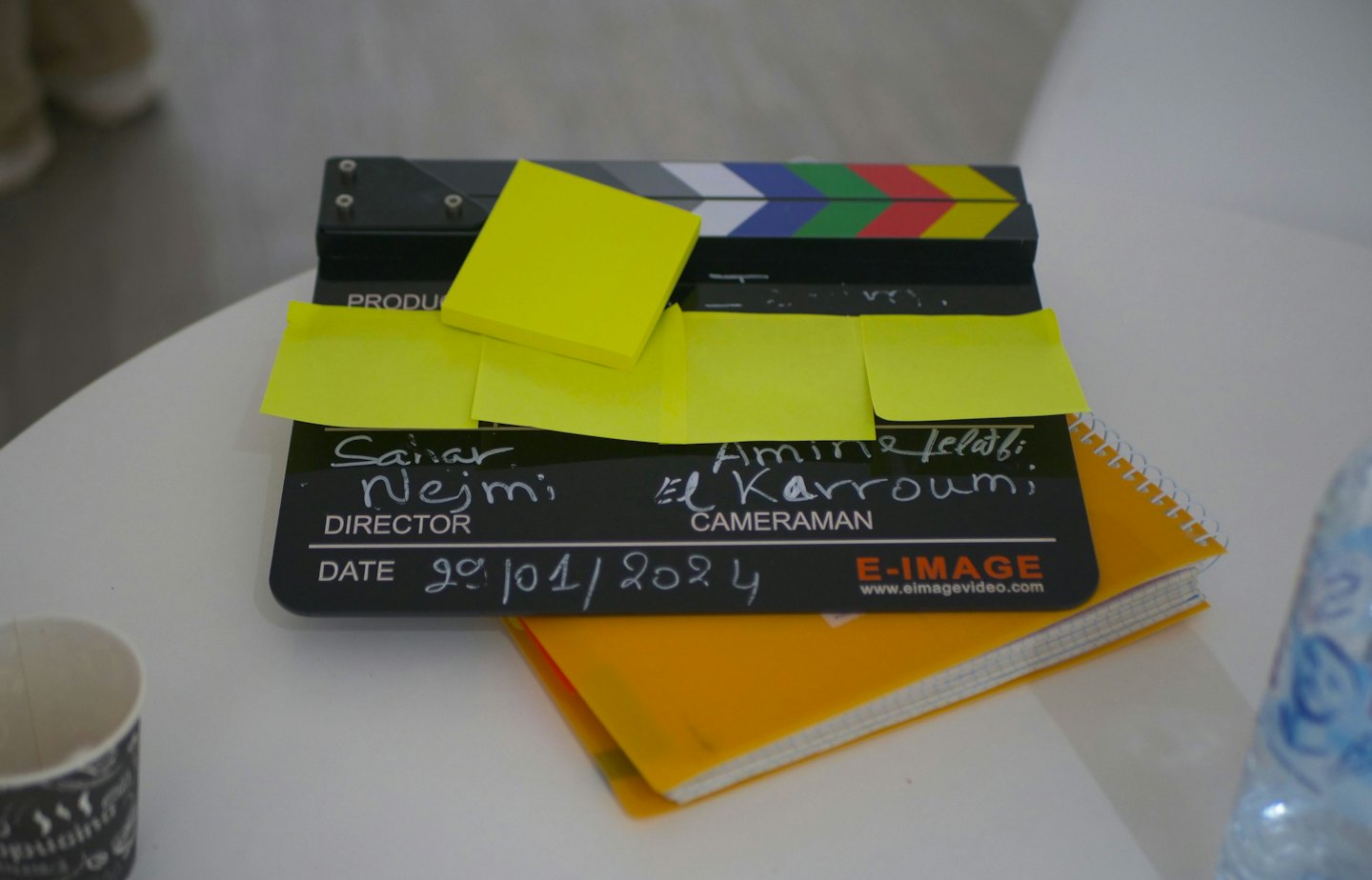 Film clapperboard with sticky notes resting on a notebook.