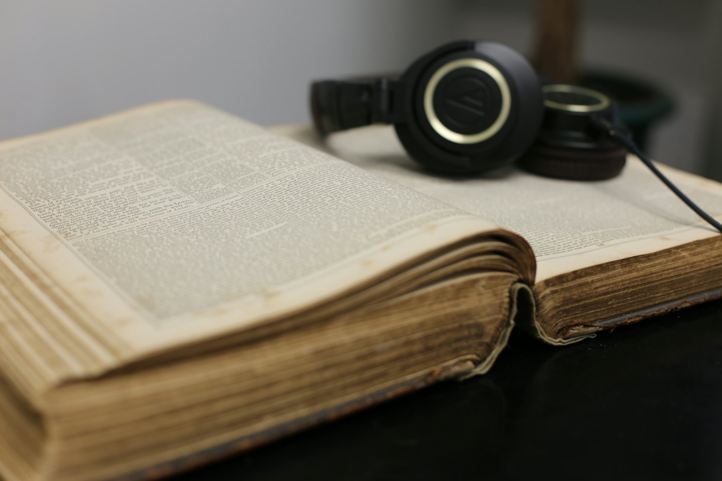 Modern headphones rest on the pages of an antique book.