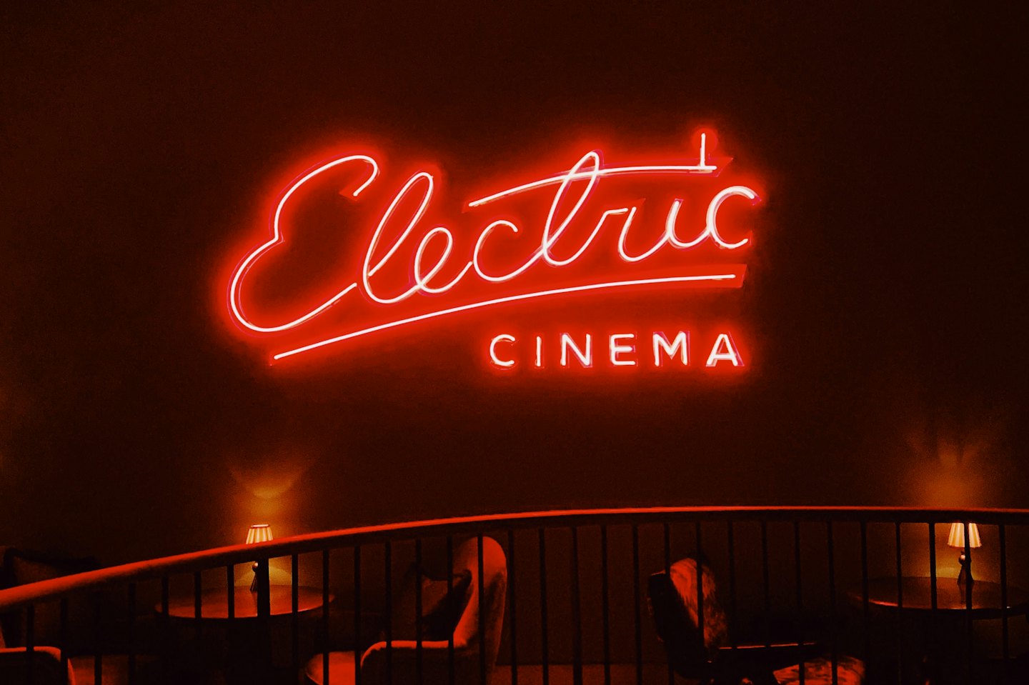 A glowing red Electric Cinema neon sign above lounge seating.